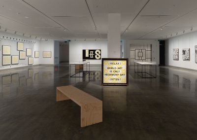 A wider shot of a gallery with many artworks by Peter Tyndall in a gallery with no people